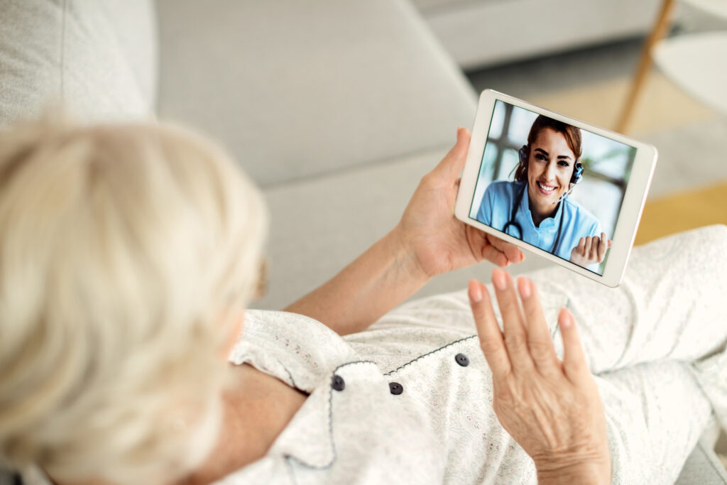 Télémédecine : femme âgée consultant un médecin à distance depuis son canapé